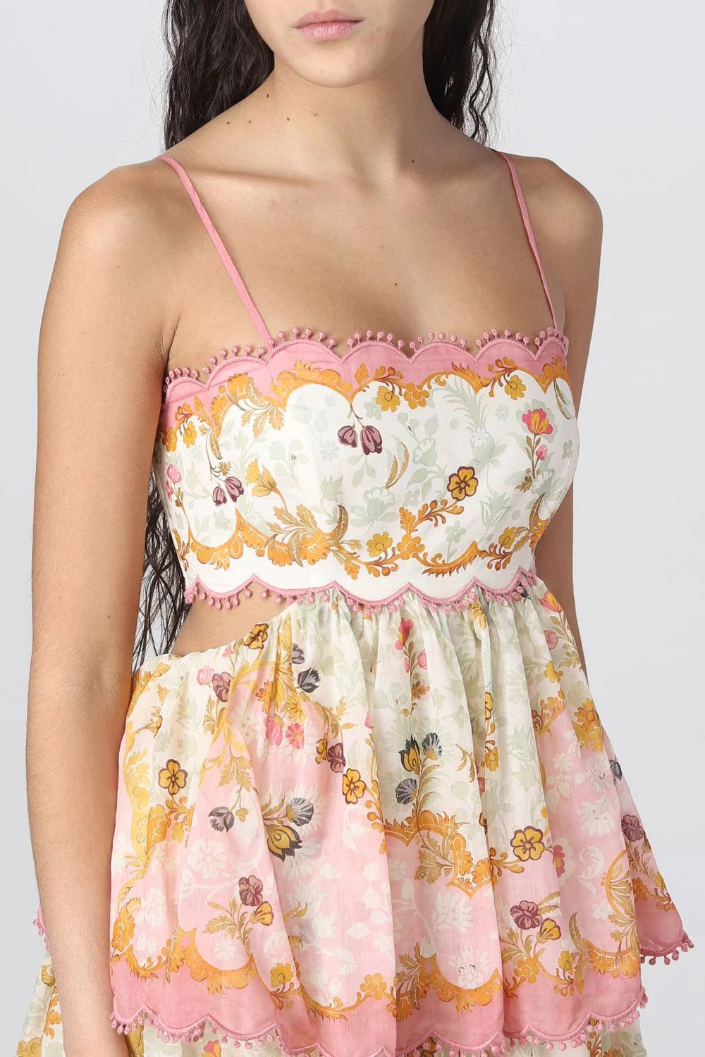 Close-up of a woman wearing a floral print maxi dress with pink scalloped trim and spaghetti straps