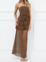 Woman wearing a brown strapless maxi dress with tiered ruffles and a sheer overlay, front view.