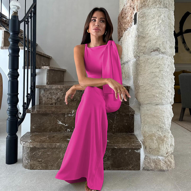 Woman in a hot pink sleeveless column gown with an asymmetrical neckline sitting on a marble staircase.