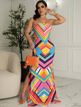 woman wearing a colorful geometric print strapless maxi dress with a high slit and orange accessories