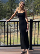 Woman wearing a black maxi dress with spaghetti straps standing on a balcony