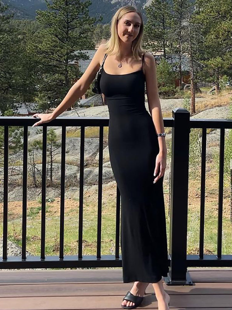 Woman wearing a black maxi dress with spaghetti straps standing on a balcony