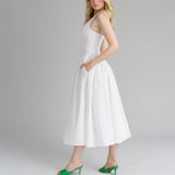 Woman in a white halter dress with pockets, showing the side view.