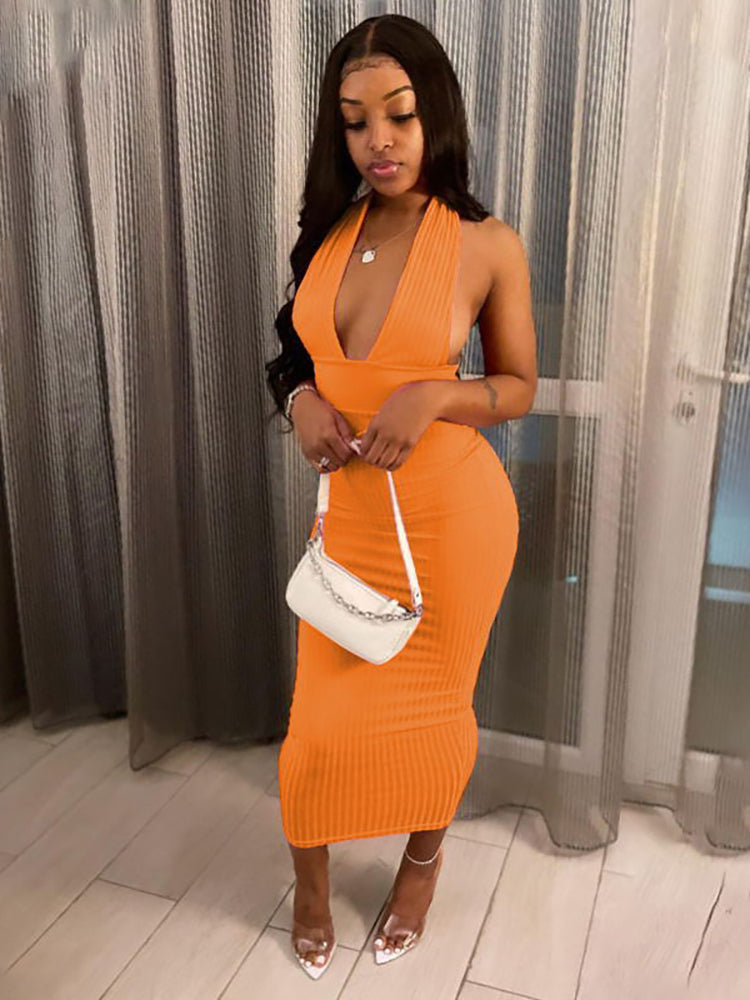 Woman wearing an orange halter neck bodycon midi dress with a plunging neckline and open back.