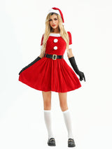 Woman in a festive red velvet Christmas dress, posing with her hands on her hips.