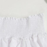 Close-up of the smocked neckline of a white off-the-shoulder dress.