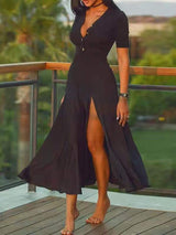 Woman wearing a black short-sleeved midi dress with a deep V-neck and a high slit