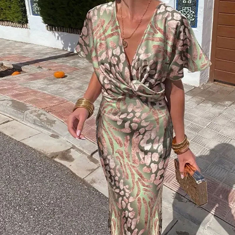 Woman wearing a green and pink animal print satin maxi dress with a V-neckline and twisted front detail.