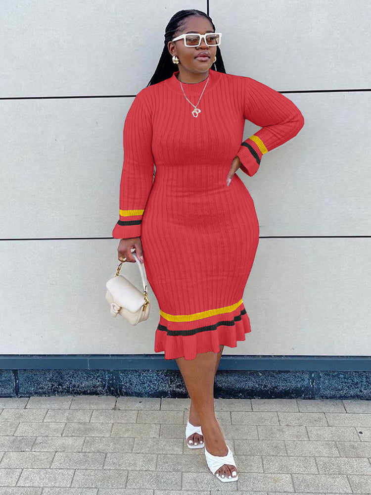 Woman wearing a red ribbed knit midi dress with striped cuffs and hem, holding a white handbag.