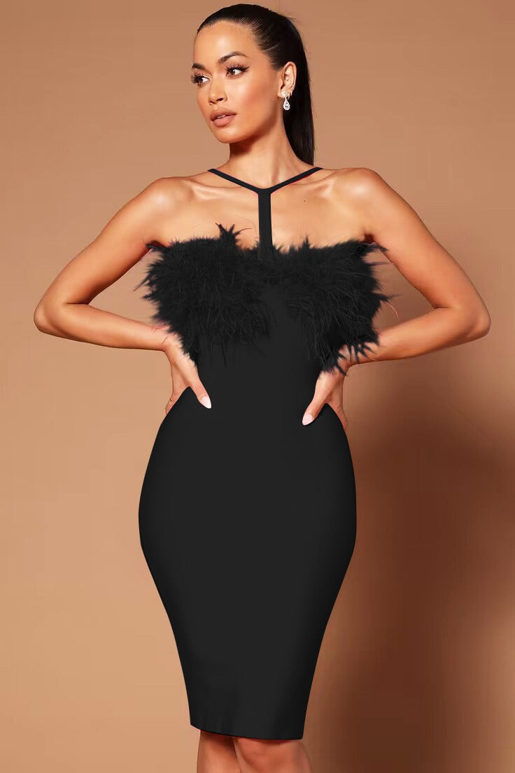Woman wearing a black bandage midi dress with feather trim and a halter neckline, hands on hips.