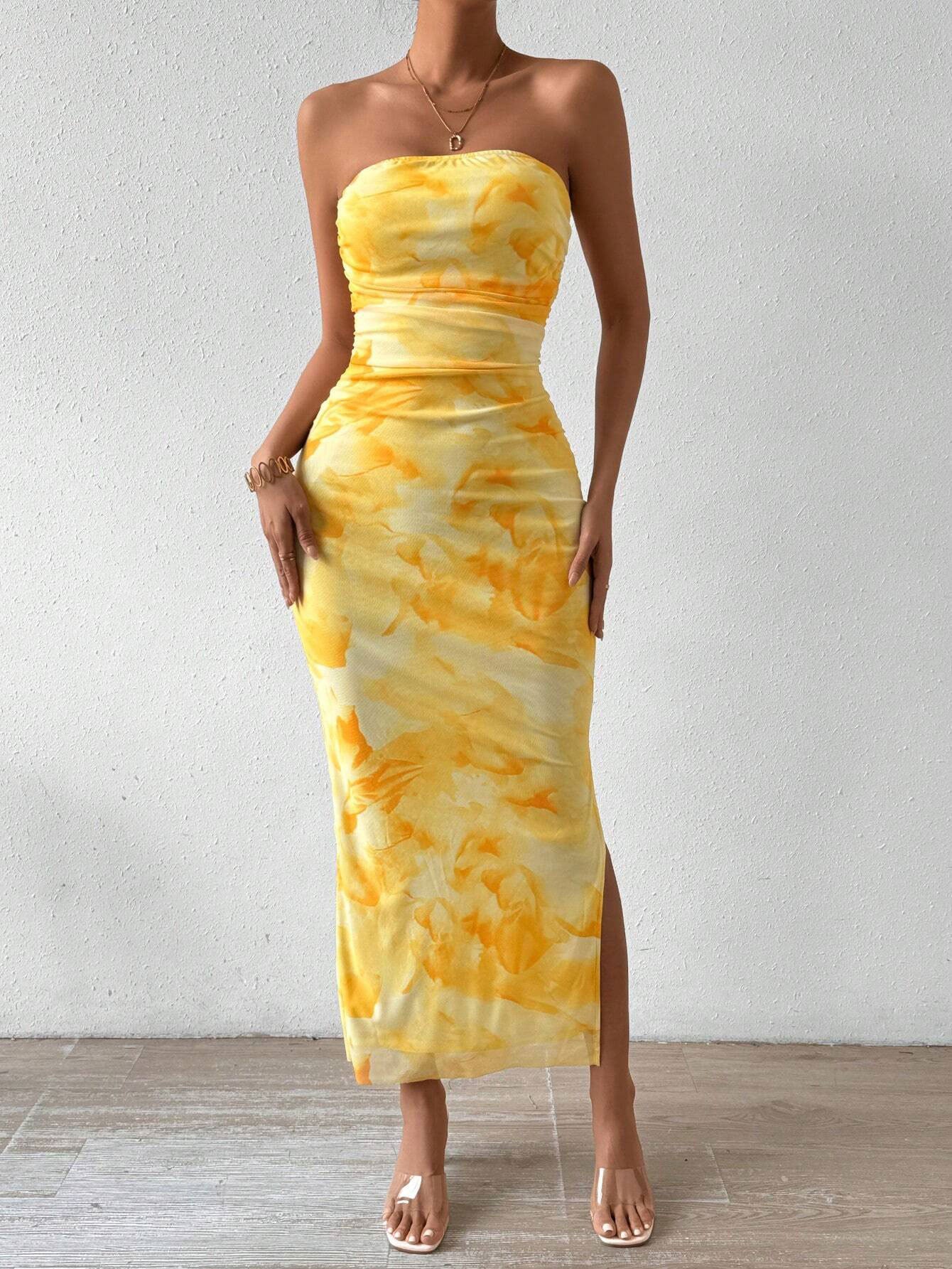 Full-length view of a woman in a yellow tie-dye print strapless maxi dress.