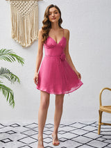 Woman wearing a pink A-line dress with spaghetti straps and a v-neckline.