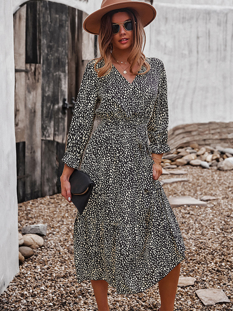 Woman wearing a black and yellow polka dot midi dress, brown hat, sunglasses, and holding a black clutch.
