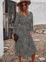 Woman wearing a black and yellow polka dot midi dress, brown hat, sunglasses, and holding a black clutch.