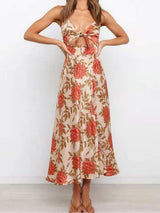 Woman wearing a floral print satin dress with a cut-out and thigh-high slit, standing with her hands on her hips and looking forward.
