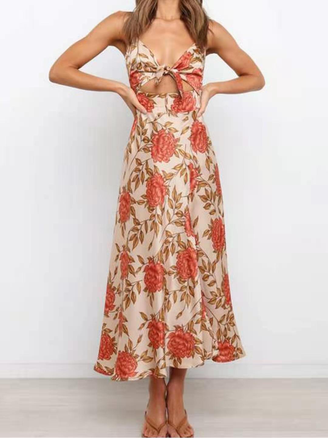 Woman wearing a floral print satin dress with a cut-out and thigh-high slit, standing with her hands on her hips and looking forward.