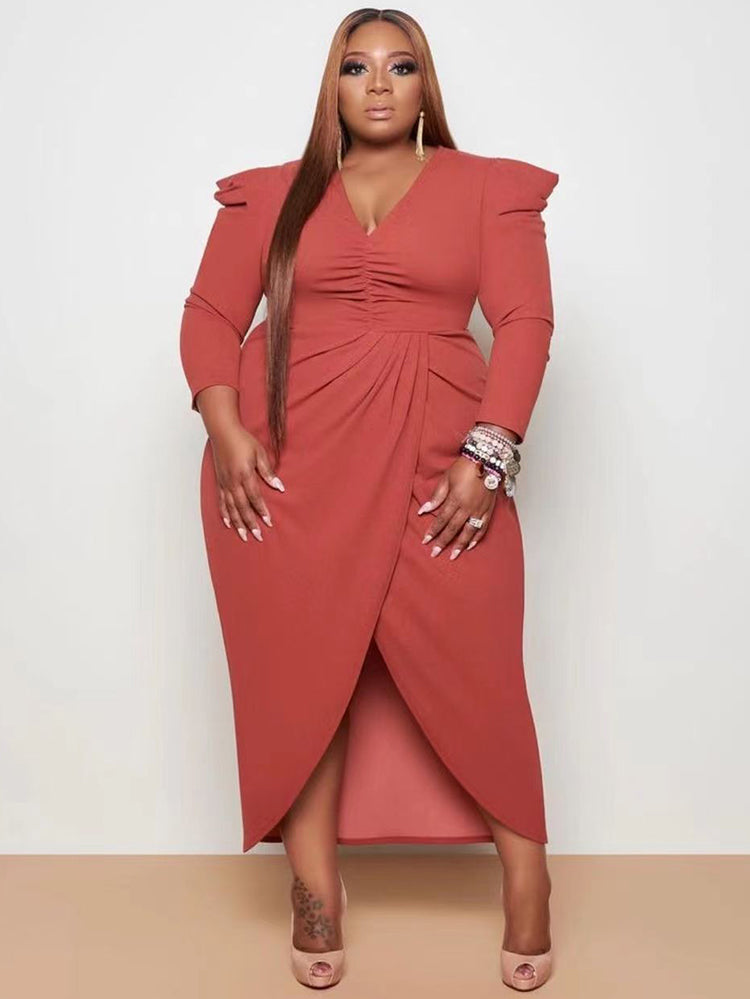 Woman wearing a rust ruched V-neck sheath dress with an asymmetrical tulip hem and puffed shoulders.