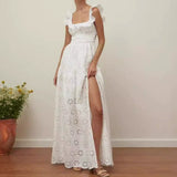 Woman wearing a white eyelet maxi dress with a square neckline and ruffled straps, showing a high slit