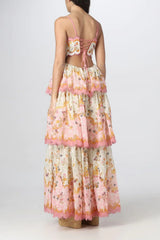 Back view of a woman wearing a tiered floral print maxi dress with a lace-up back and spaghetti straps.
