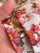 A white belt cinching the waist of a floral print midi dress.