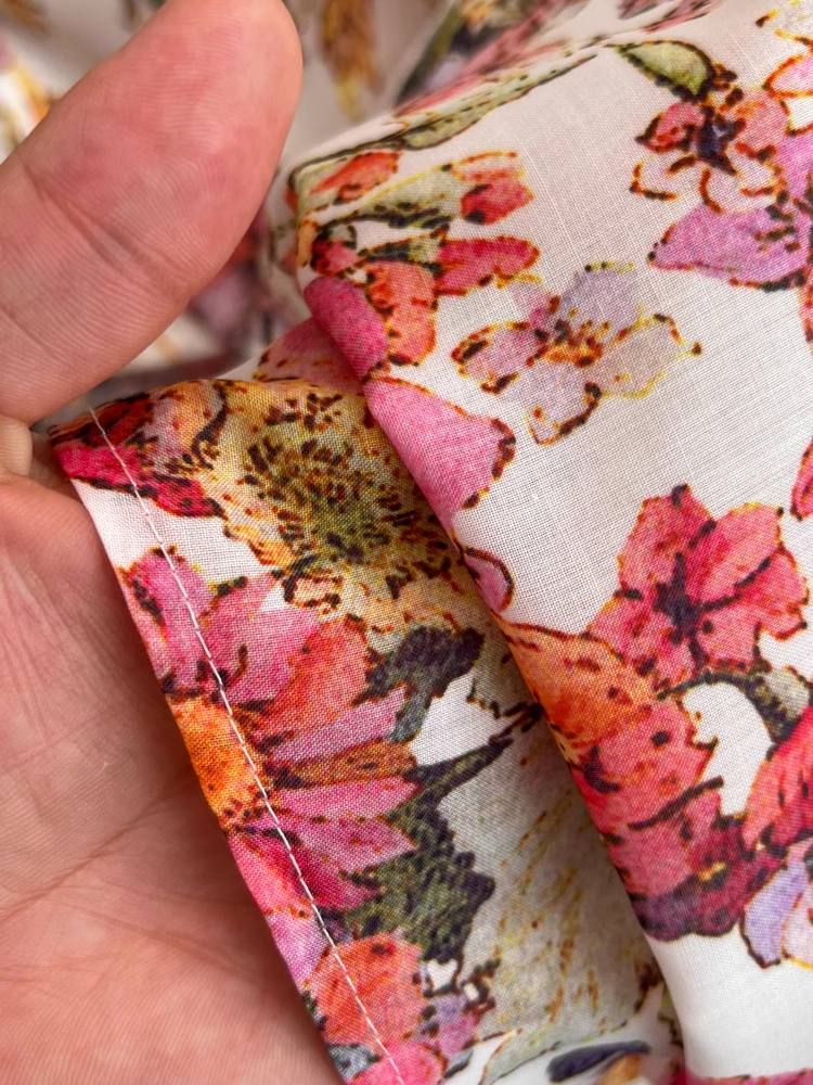 A white belt cinching the waist of a floral print midi dress.