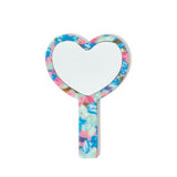 A heart-shaped hand mirror with a multi-colored tortoiseshell pattern and a white reflective surface.