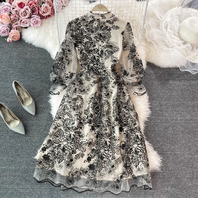 Close-up of the bodice of a black and white floral embroidered midi dress, highlighting the sheer fabric, sequins, and mock neckline.
