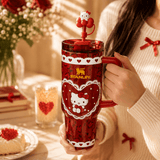 Person holding a red Stanley tumbler with Hello Kitty design, surrounded by festive decor.