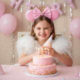 Girl wearing pink sequin Minnie Mouse ears headband with a crown and bow, celebrating a birthday with a cake