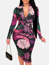 Woman in a black midi dress with a pink and purple leaf print, V-neck, long sleeves, and a belted waist.