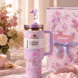 Floral-patterned Stanley tumbler with matching gift box on a decorative surface.