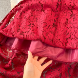 Close-up of the hem of the red lace dress, revealing the lining and the intricate lace detail.