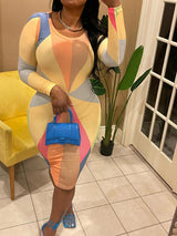 Woman wearing a long-sleeved, multi-colored geometric print bodycon dress with a crew neck, holding a blue handbag and blue strappy heels.