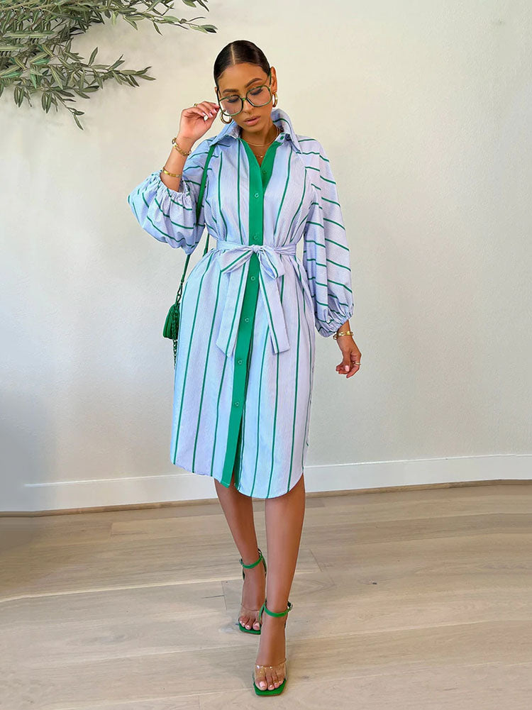 Woman wearing a light blue and green striped shirt dress with a belted waist and balloon sleeves.
