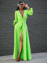 Woman wearing a vibrant lime green long sleeve maxi dress with a deep V-neck, button-down front, self-tie belt, and a high slit, accessorized with a headscarf and sunglasses.