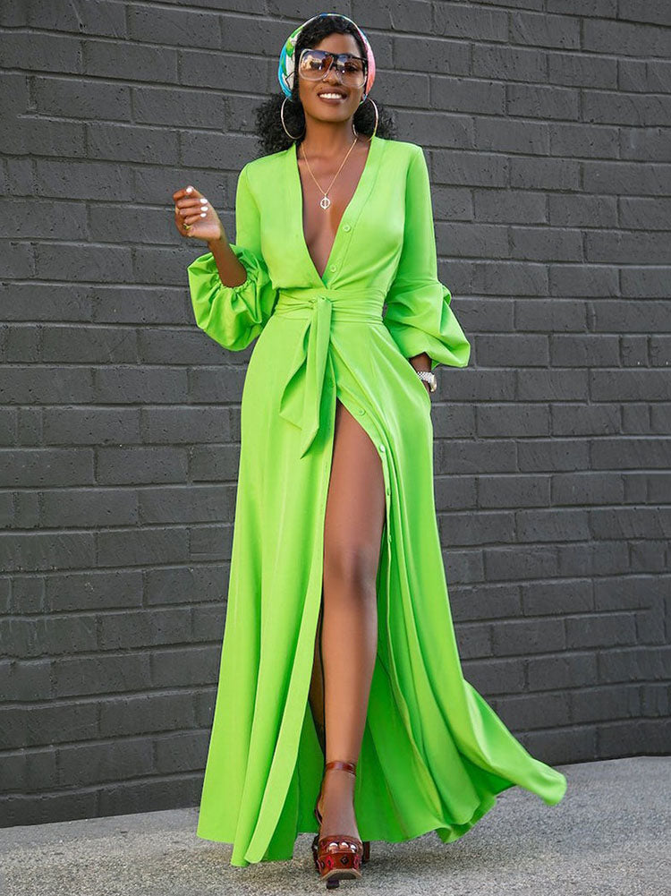 Full body shot of a woman in a lime green maxi dress with a V-neck, button details, and a belted waist, showcasing the high slit.