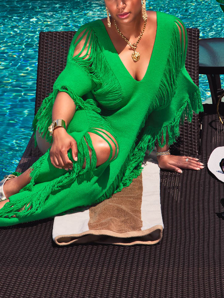Woman relaxing by a pool in a green distressed knit maxi dress with fringe detailing.