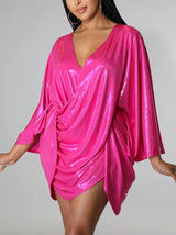 Model posing in a dazzling pink wrap dress with a deep V-neck.