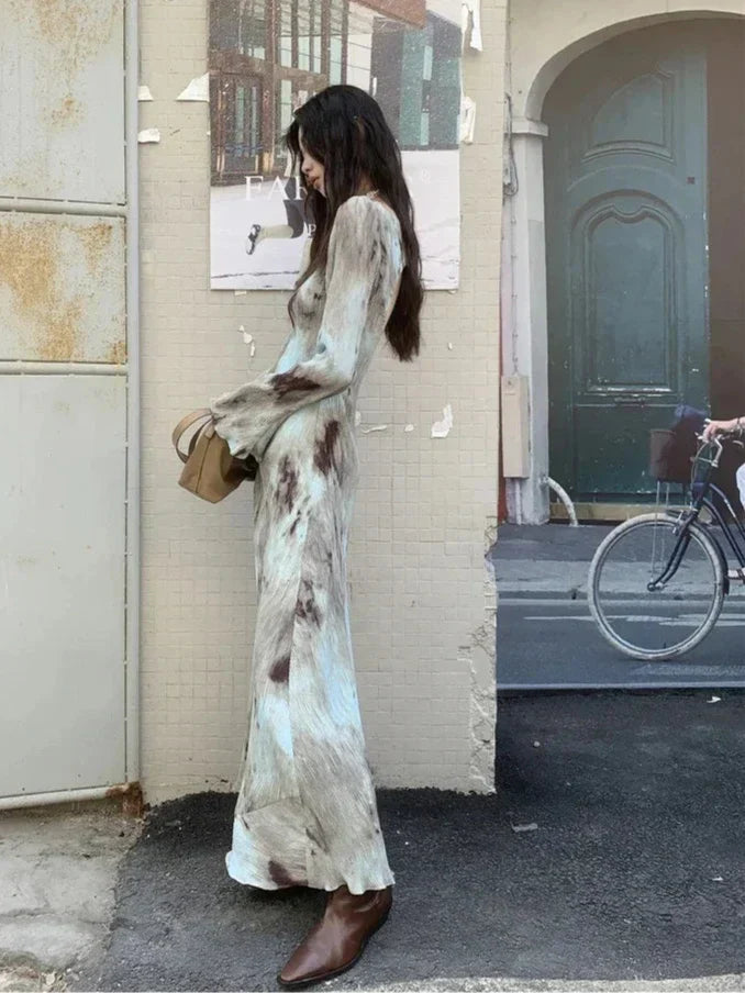 Side view of a woman in a tie-dye maxi dress, showcasing the flowing silhouette and flared cuffs.