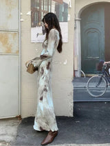 Side view of a woman in a tie-dye maxi dress, showcasing the flowing silhouette and flared cuffs.