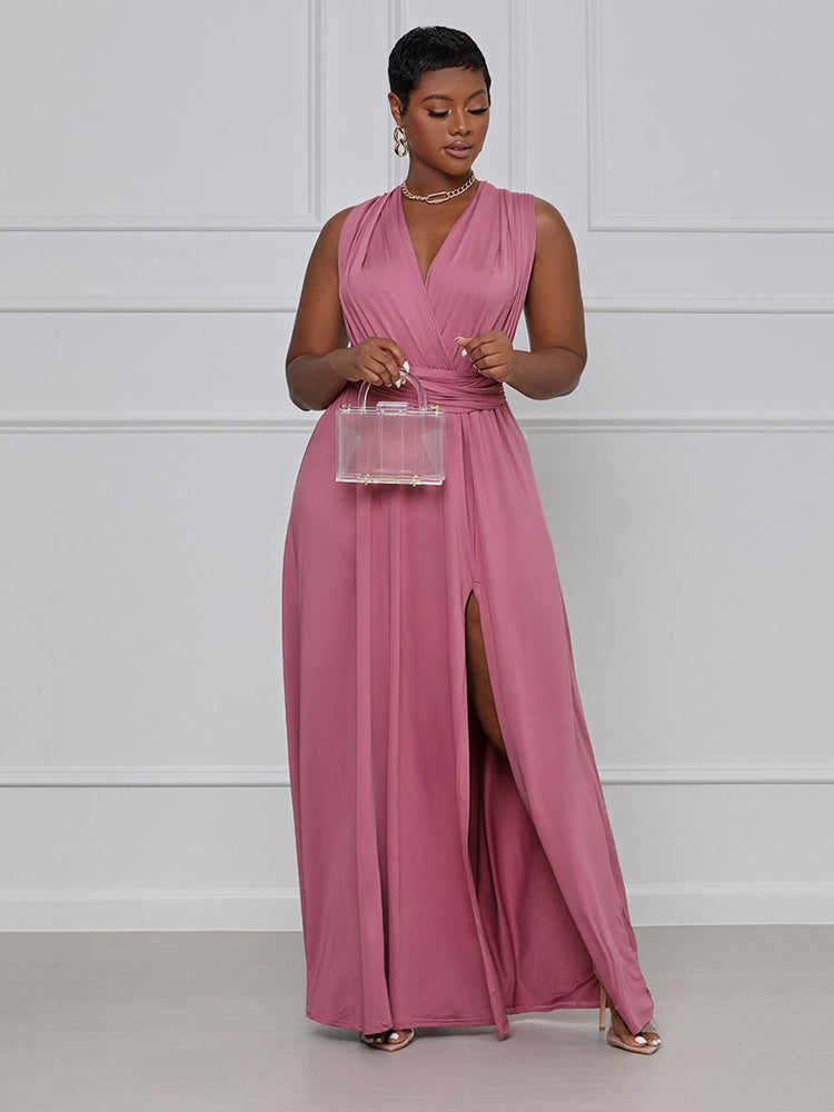 Woman wearing a dusty rose maxi dress with a V-neck and high slit, holding a clear handbag.