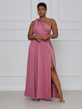 Woman wearing a dusty rose maxi dress styled as a one-shoulder with a high slit.