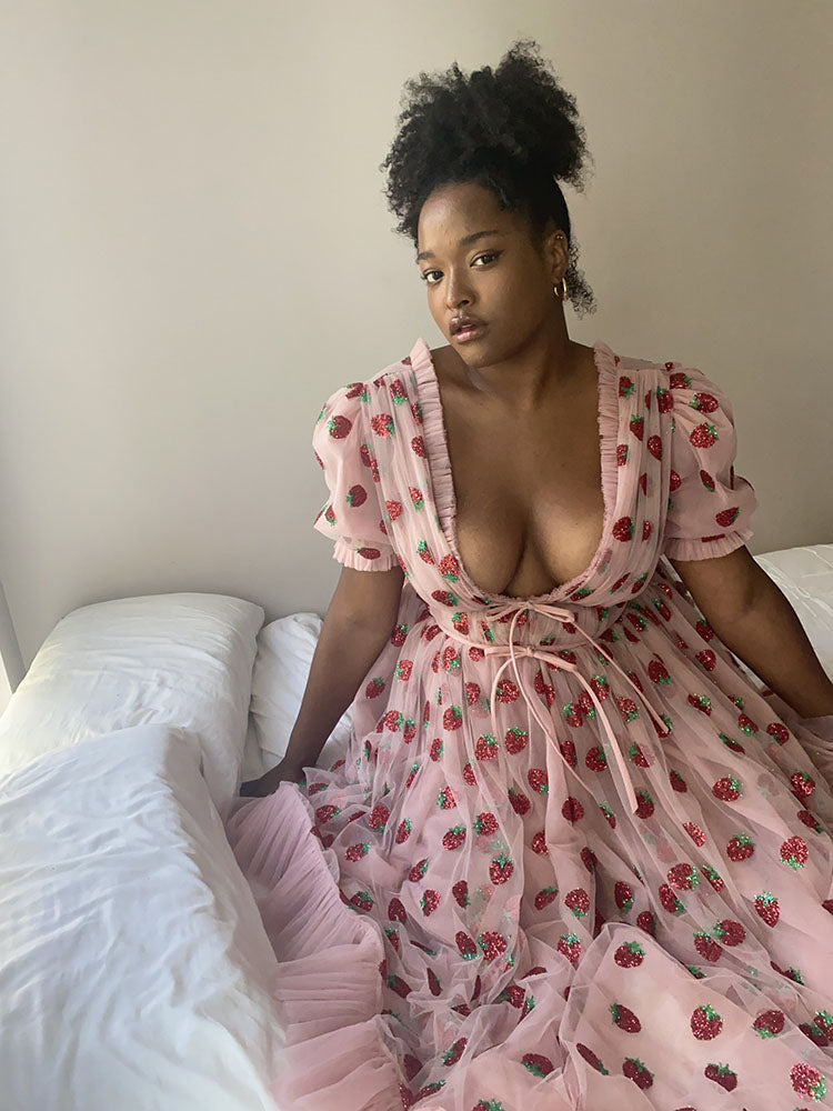 Woman in strawberry print dress on bed