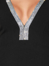Detailed view of the rhinestone embellishment on the V-neckline of a black dress.