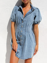 Close-up of a light blue denim shirt dress with puff sleeves and button-down front.