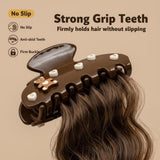 Close-up of a brown hair claw clip with teddy bear and heart designs holding a section of brown hair, highlighting its "Strong Grip Teeth"