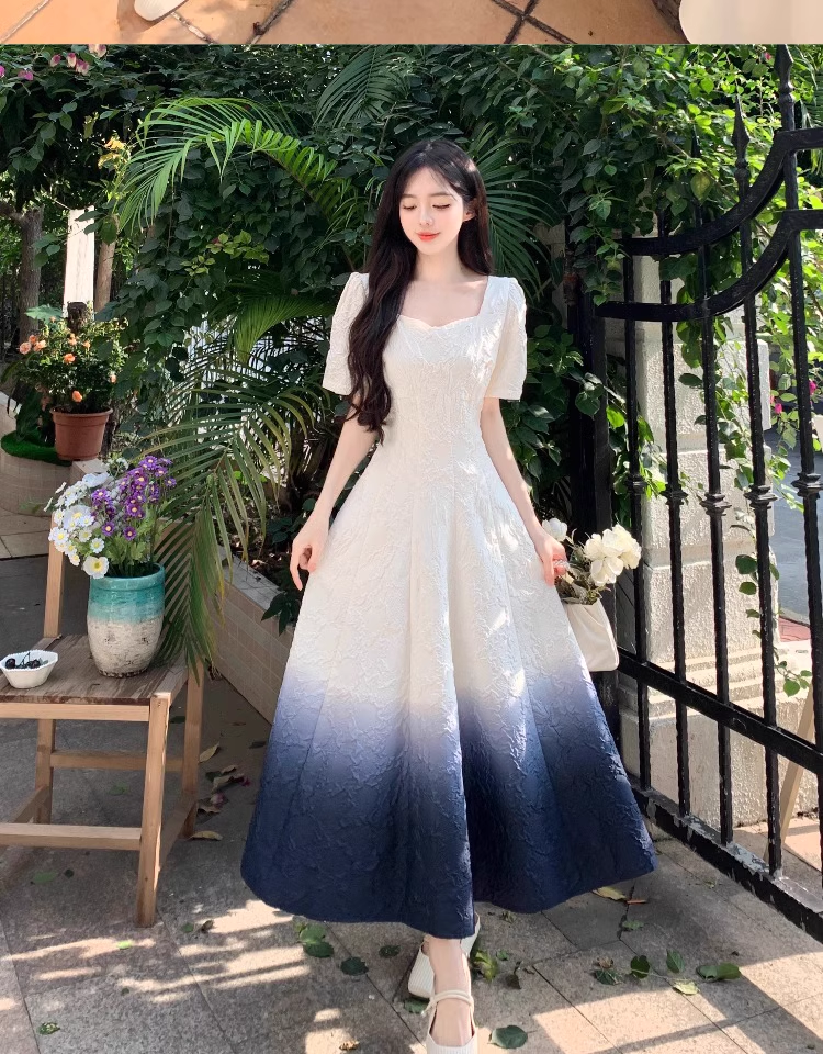 Woman wearing a white and dark blue ombre gradient fit and flare midi dress with puff sleeves, standing outdoors.