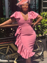 woman wearing a pink ruffled dress and a fascinator