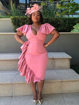 woman in a pink ruffled dress with a fascinator on stairs