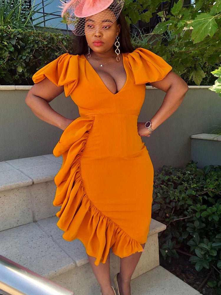 woman wearing an orange ruffled dress and a fascinator